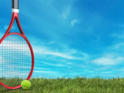 Red tennis racket standing with tennis ball on grass