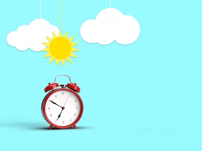 3D red alarm clock with sun and clouds on blue background.