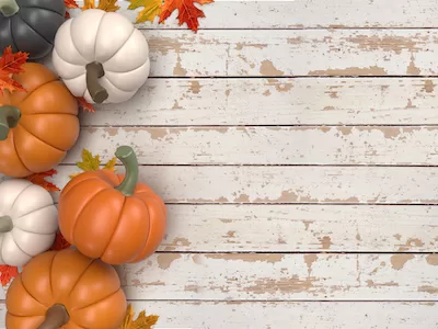 3D pumpkins with autumn leaves on wooden background top view.